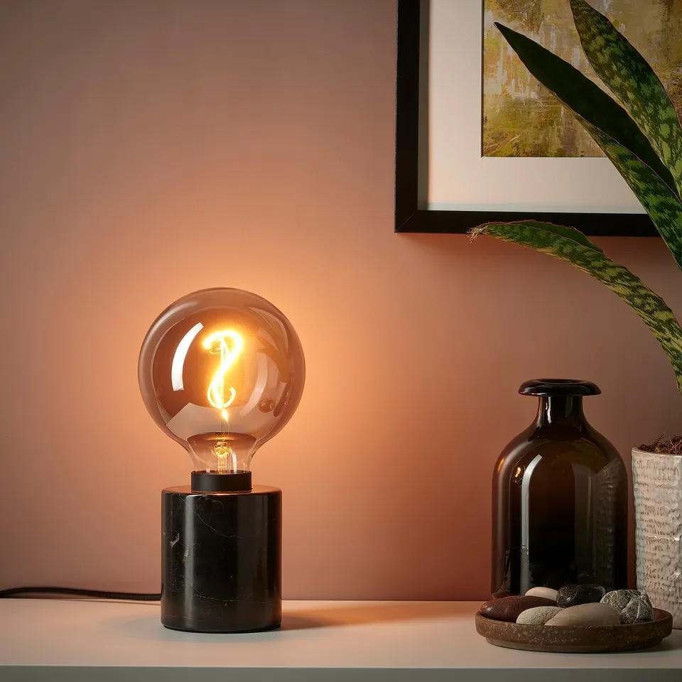 Cosy table lamp with black marble base and warm glowing led bulb.