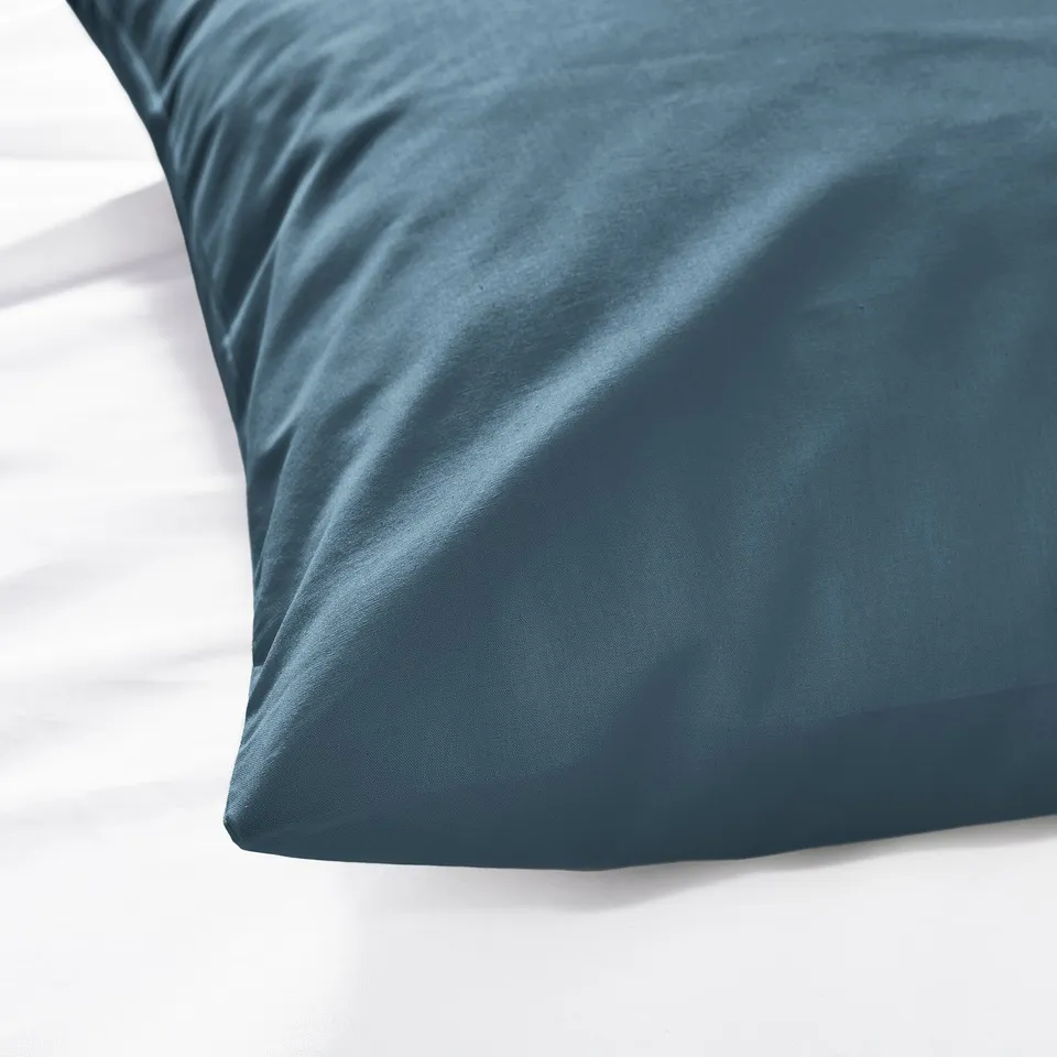 Blue pillowcase close-up, soft fabric texture visible, smooth surface.