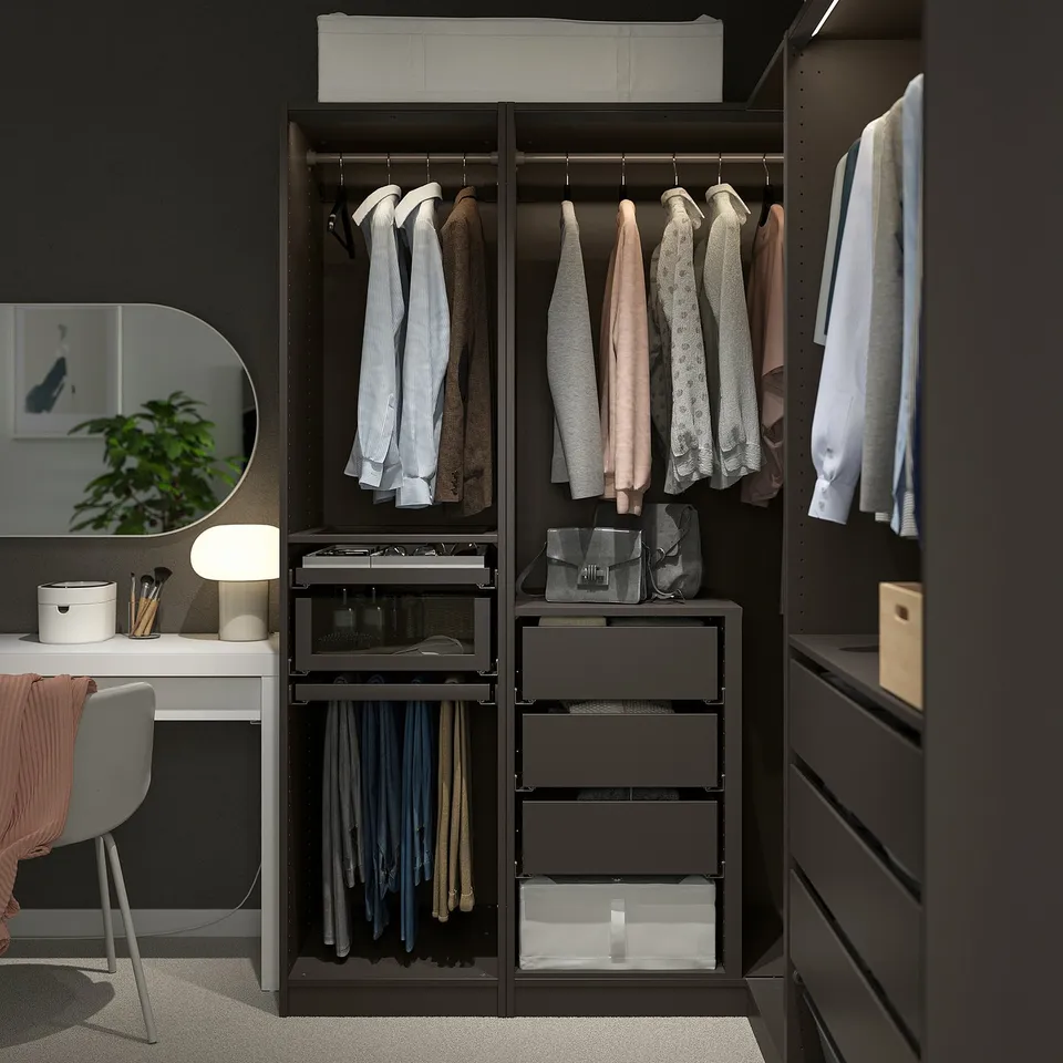 Modern black PAX wardrobe with clothes, drawers, and organisers in corner.