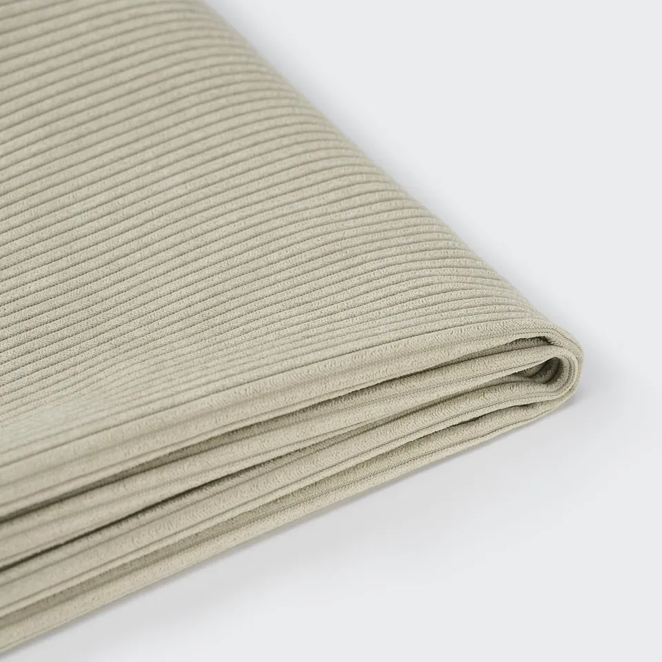 Close-up of a neatly folded, high-quality beige fabric with fine vertical stripes.