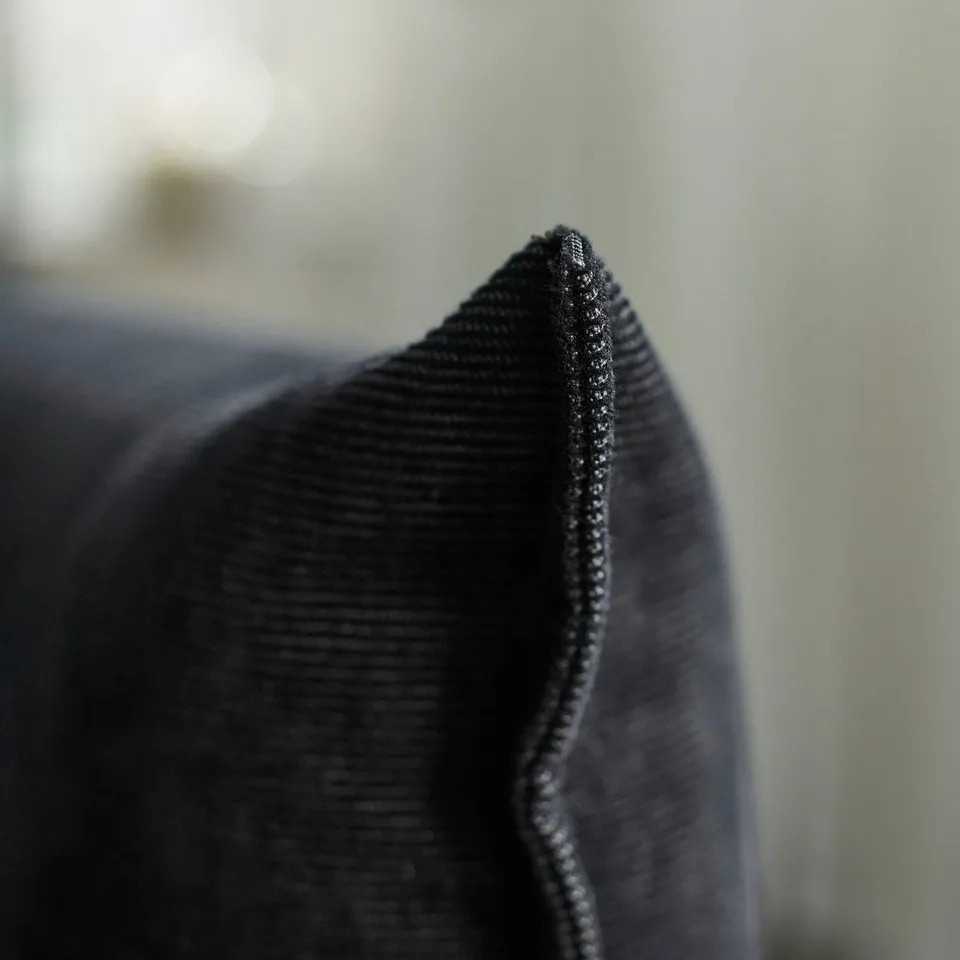 Close-up of soft, durable black fabric with neat stitching, showcasing high-quality sofa material.