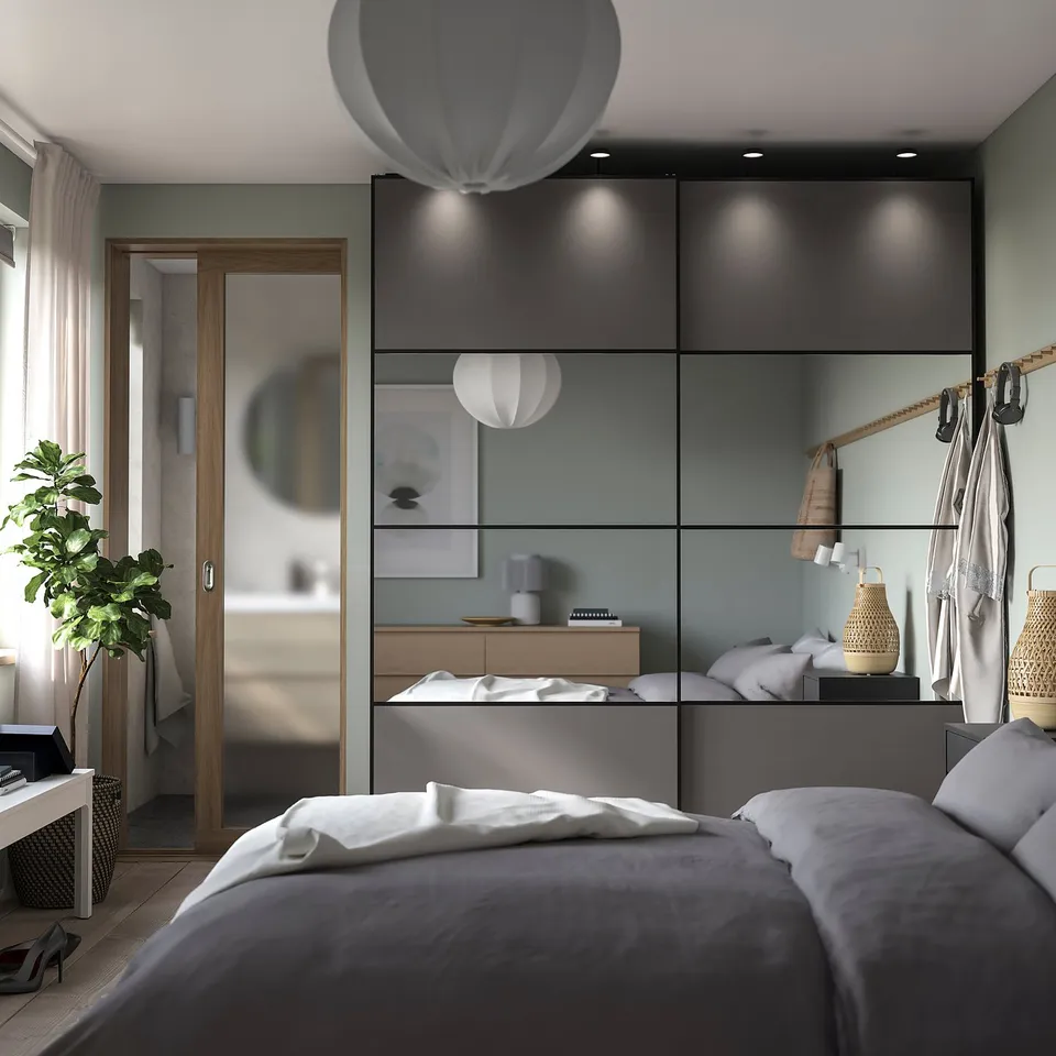 Modern bedroom featuring PAX wardrobe with grey sliding doors, white bedding, and decorative lighting.