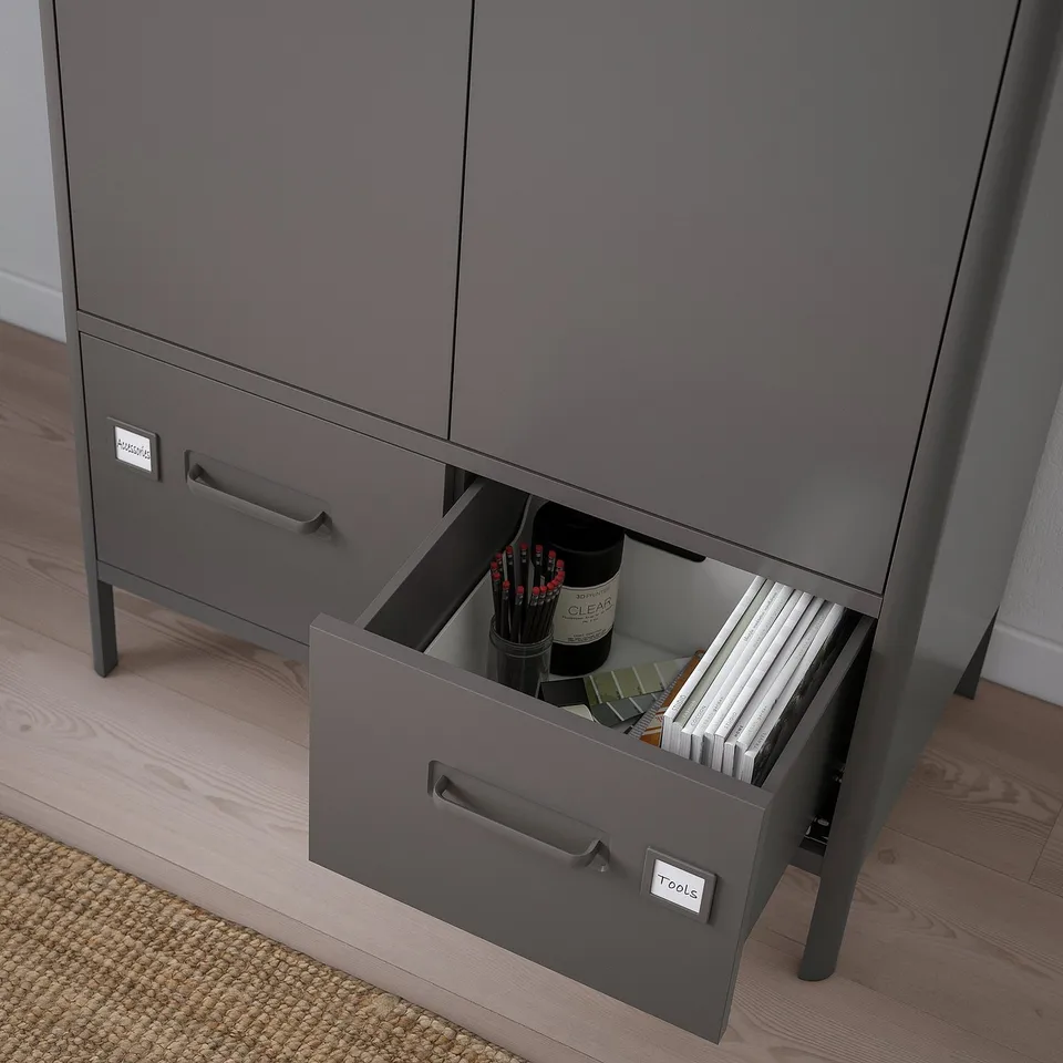 Open grey office cabinet reveals organised tools and files in bottom drawer, labelled tools.