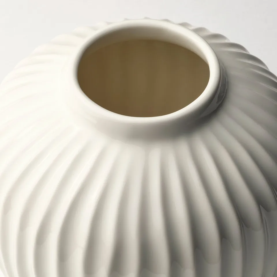 White glazed stoneware vase, smoothly textured, with intricate grooves and a rounded shape.