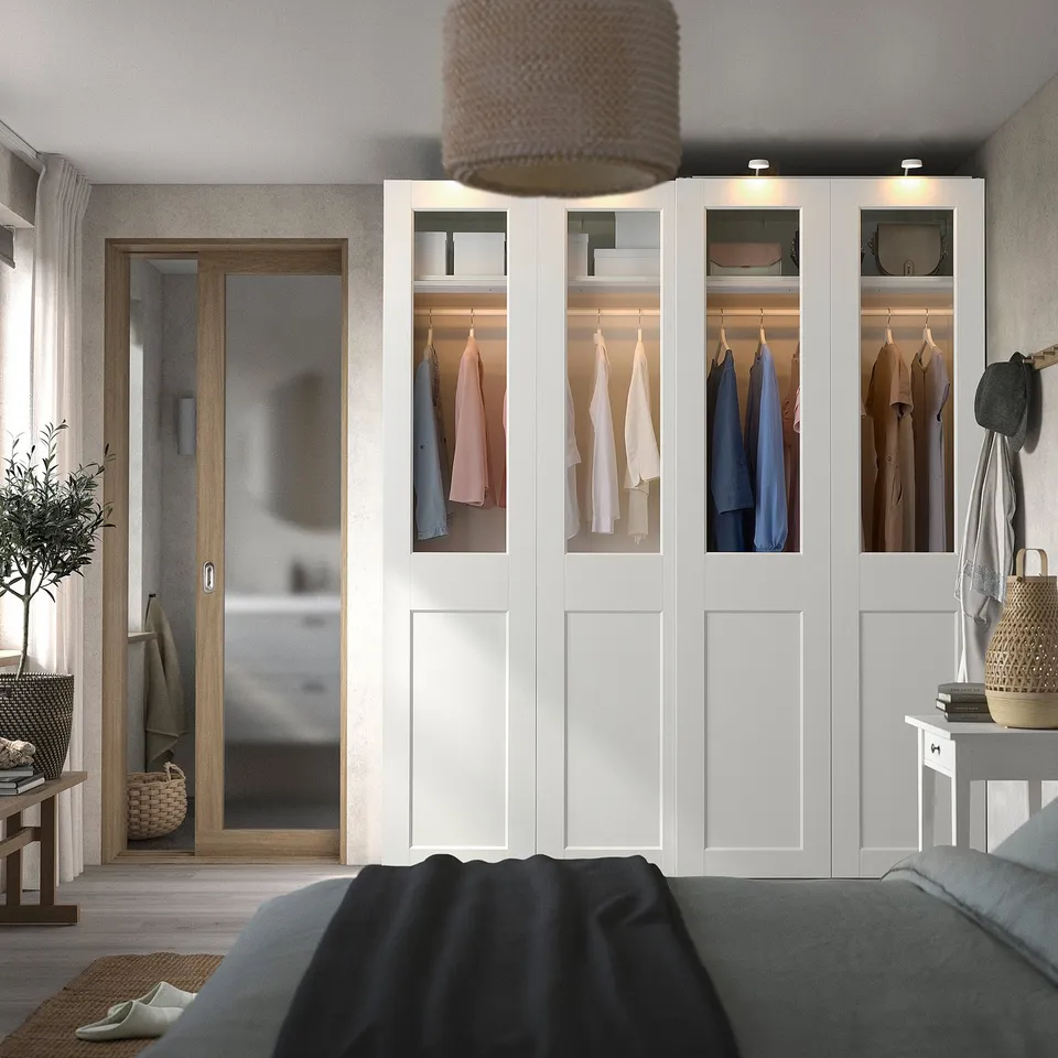 PAX wardrobe with white doors, clothes, glass top, and bed.