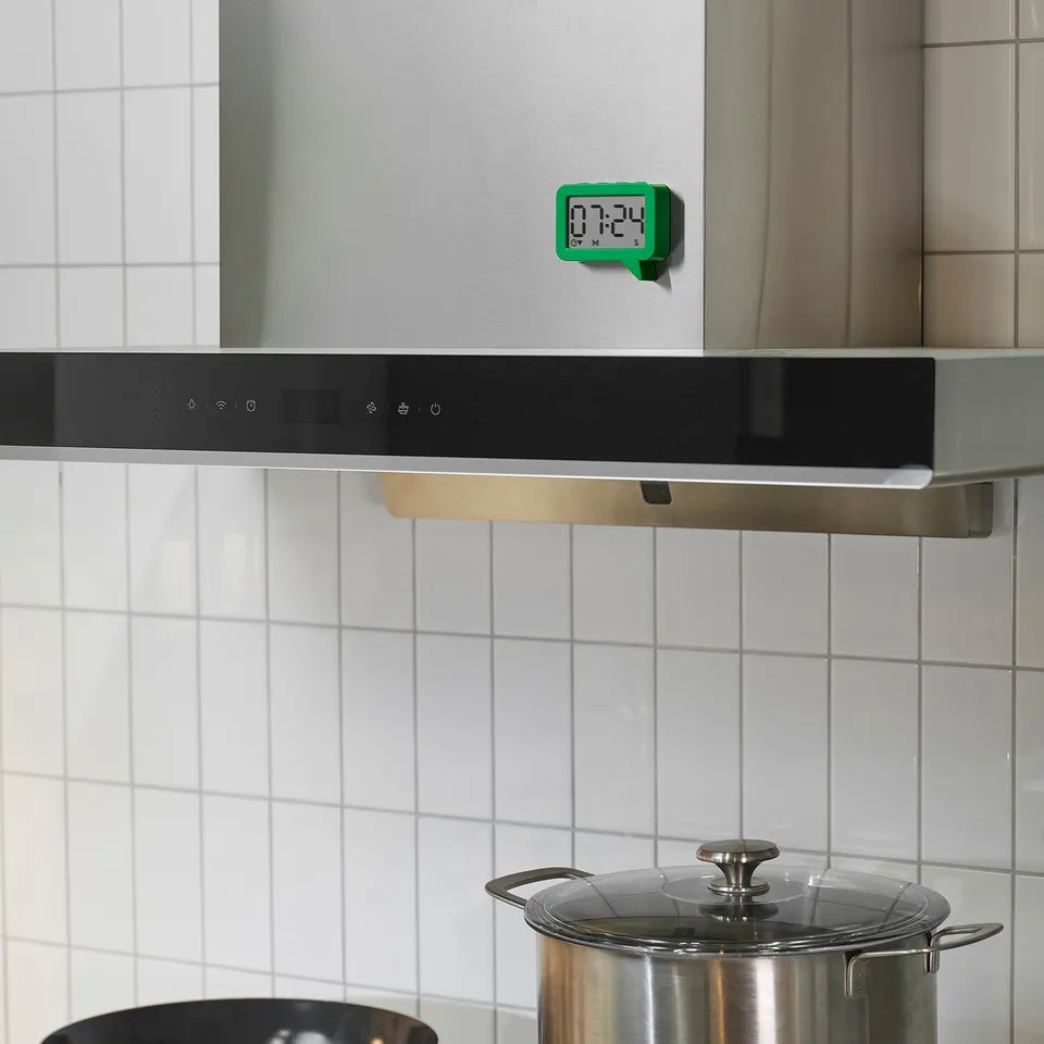 Small green LJUNGPIPARE clock magnet on stove, easy to read.