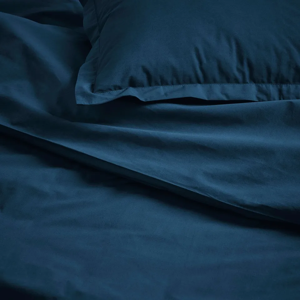 Soft, dark blue cotton sheets displayed, showing quality texture and craftsmanship.