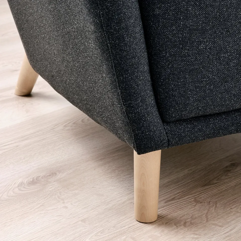 Dark grey upholstered chair with wooden legs, shown at an angle focusing on the solid, light wooden legs and the textured fabric.