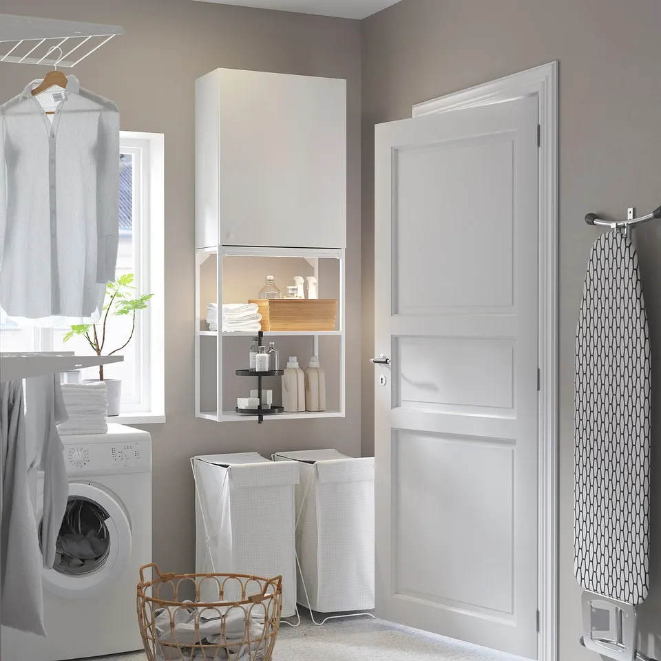 Modern white ENHET laundry setup: tall cabinet, open shelving, washing machine, baskets, and ironing board.
