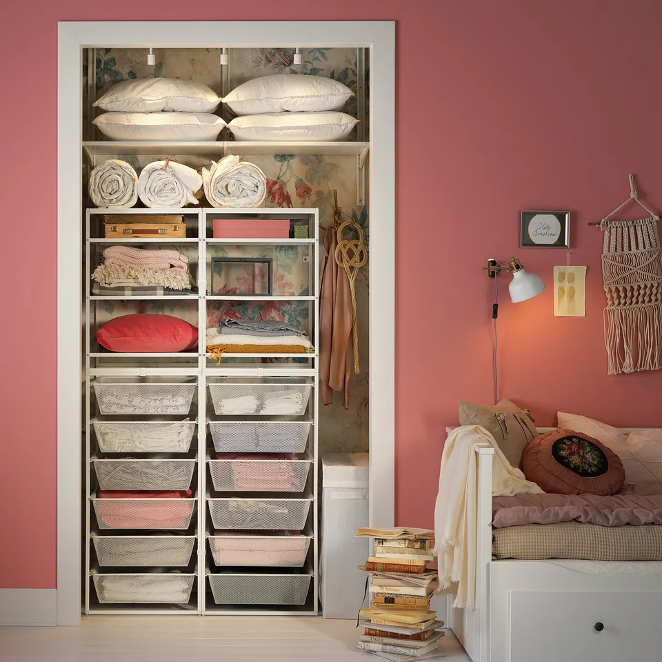 Organised room with pink walls, JONAXEL storage, baskets, bed, and books.