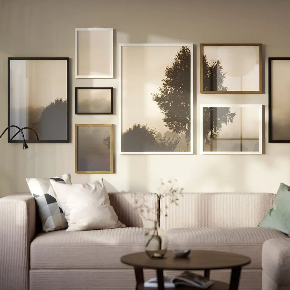 Modern living room with white RÖDALM framed art gallery on wall above light grey sofa, featuring varied sizes and nature scenes.