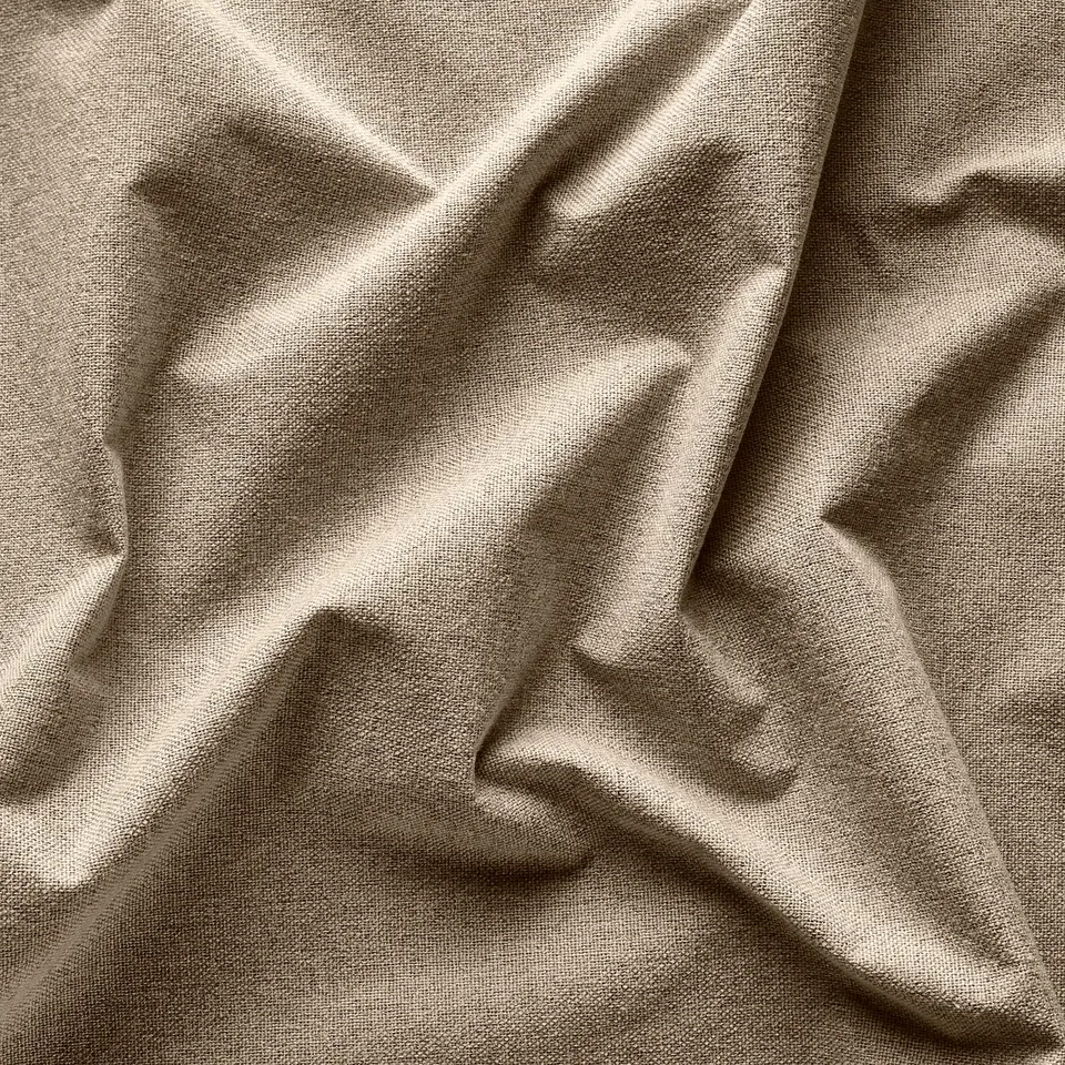 Close-up of soft, beige, textured curtain fabric with subtle weave pattern.