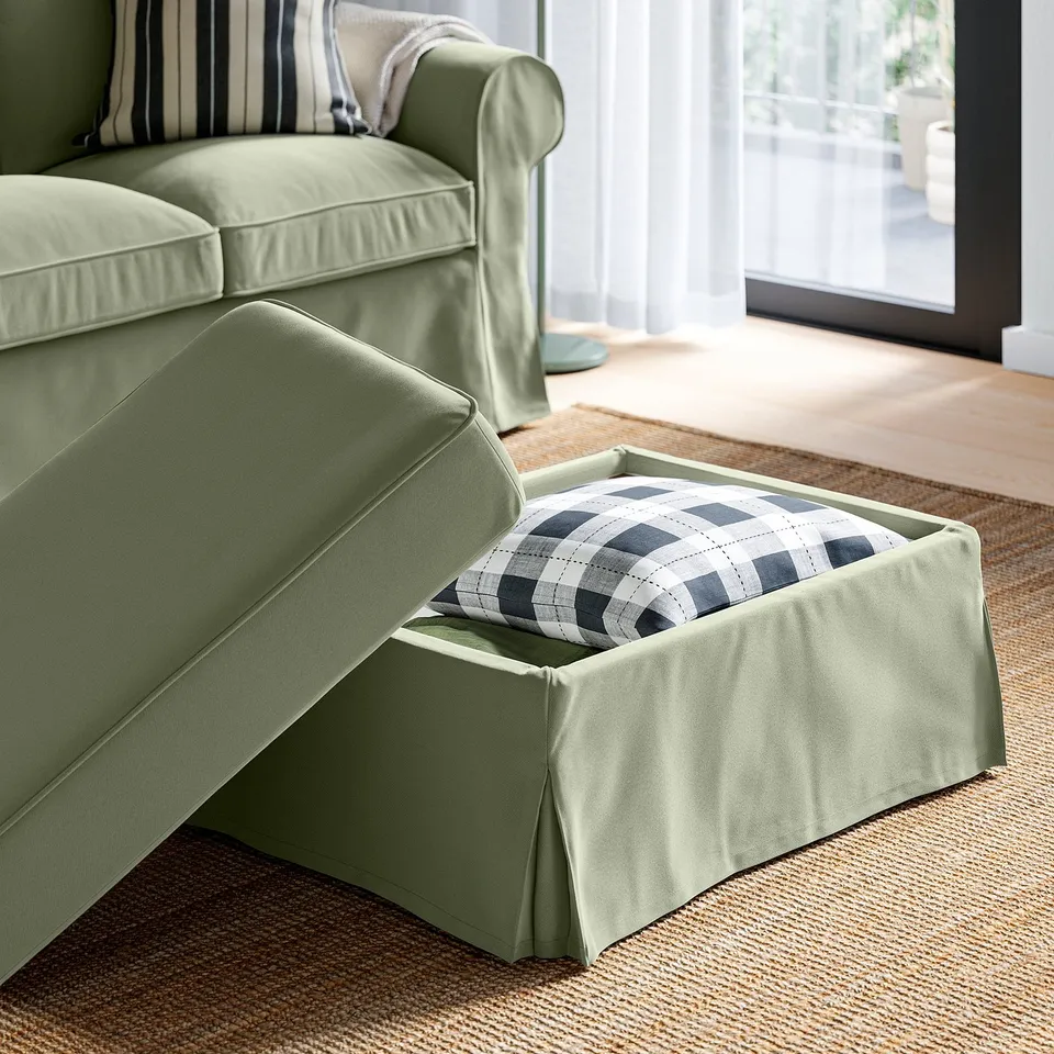 Green EKTORP footstool, with open storage space showing chequered cushion, designed for easy organisation and comfort.
