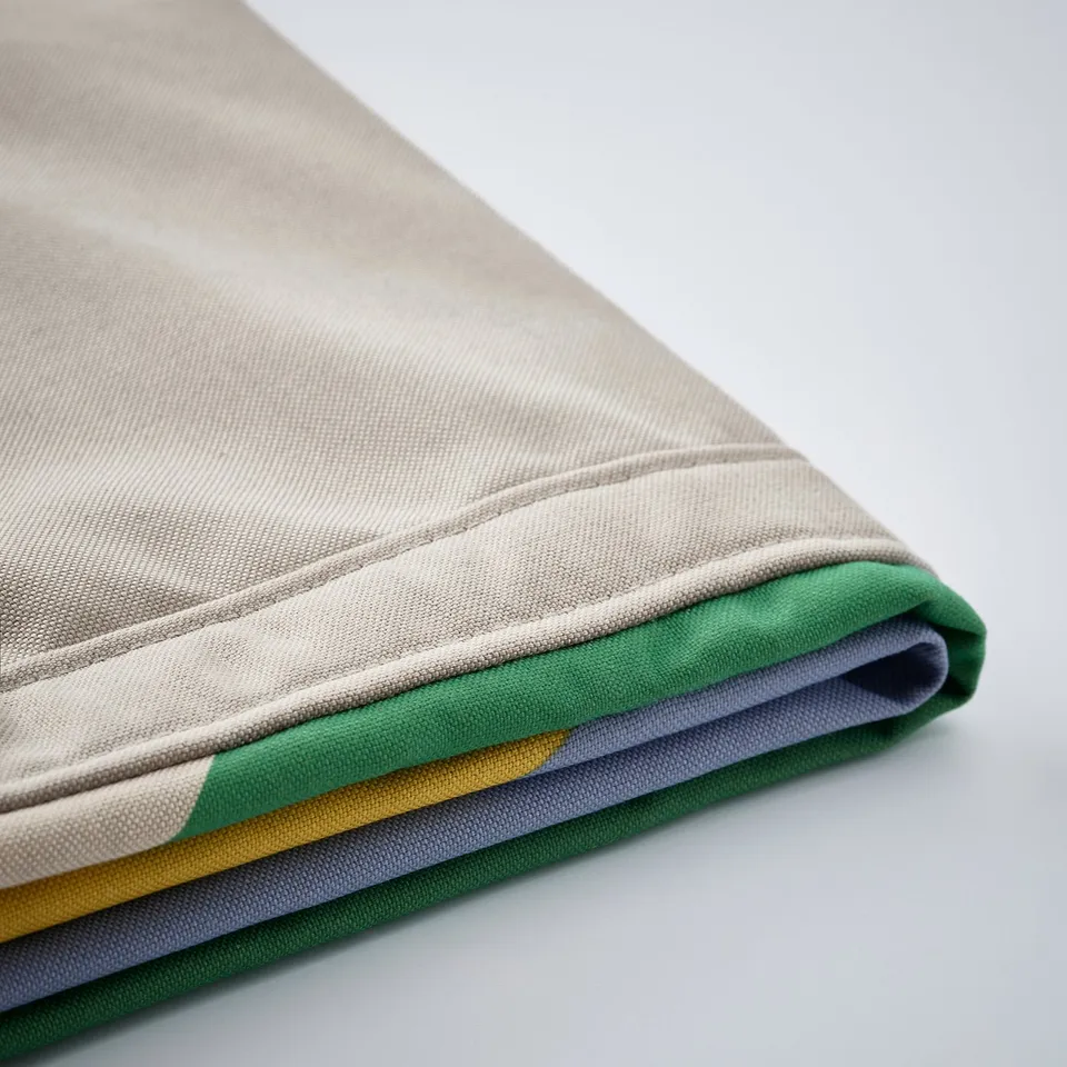 Folded fabric in beige, green, grey, and yellow, showcasing quality texture and stitching.