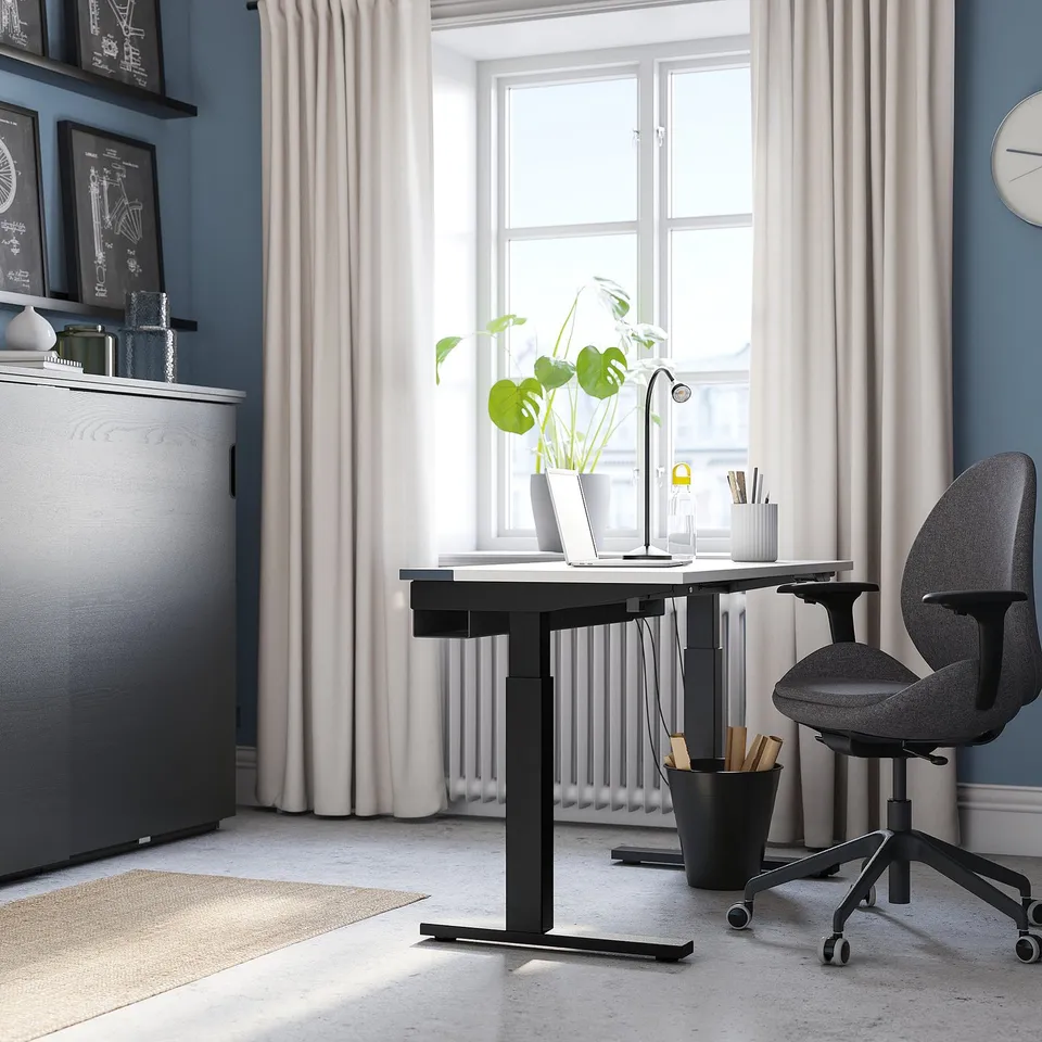 Modern home office with MITTZON desk, chair, laptop, lamp, plant, and bookshelf.