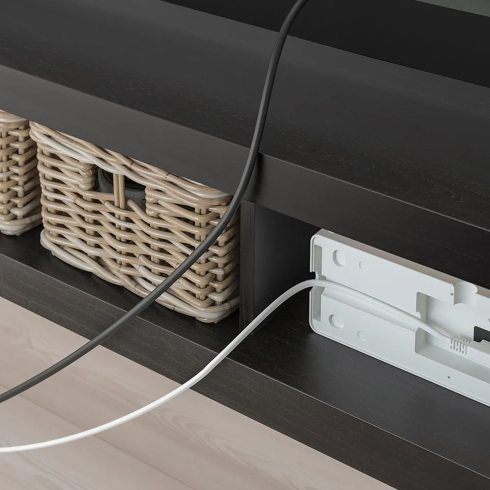 A LACK tv bench with a woven basket and cords. The cord management system is visible, highlighting its functionality in organising wires.
