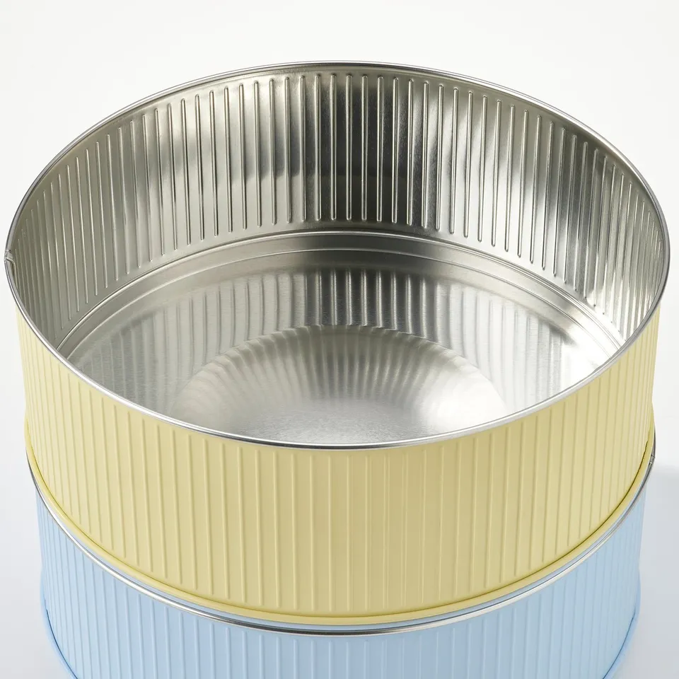 Two colourful, ribbed metal tin containers with lids, one yellow and one blue, stacked neatly.