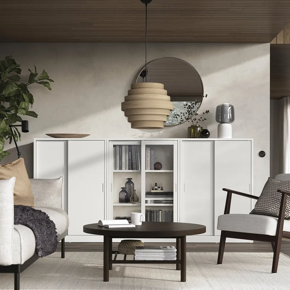 Modern living room with off-white TONSTAD cabinet, round table, and armchair. Sliding doors, adjustable shelves, and a hanging pendant light.
