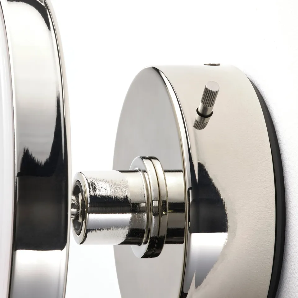 A close-up of a shiny, modern wall lamp with adjustable light and removable mirror.