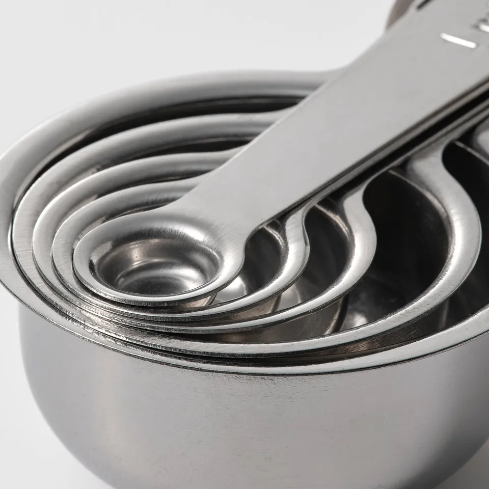 Five nested stainless steel measuring cups, clean and polished.