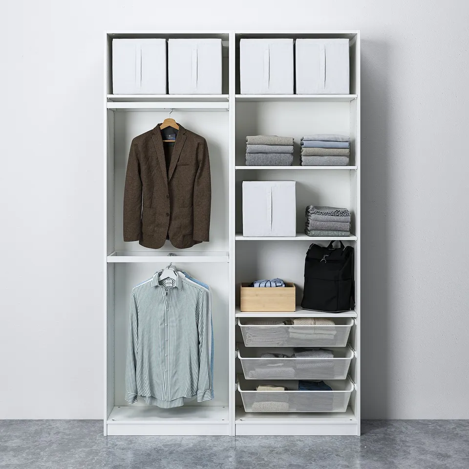 A modern, white wardrobe with hanging suits and shirts, folded clothes, baskets, and storage boxes, fixed to the wall for stability.
