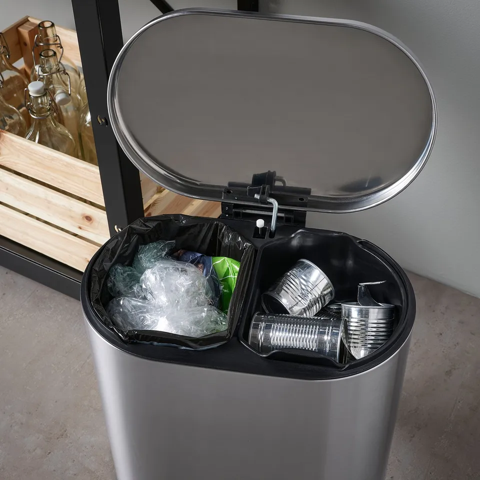 Stainless steel dual recycler bin, open showing sorted waste: cans and plastic bags.