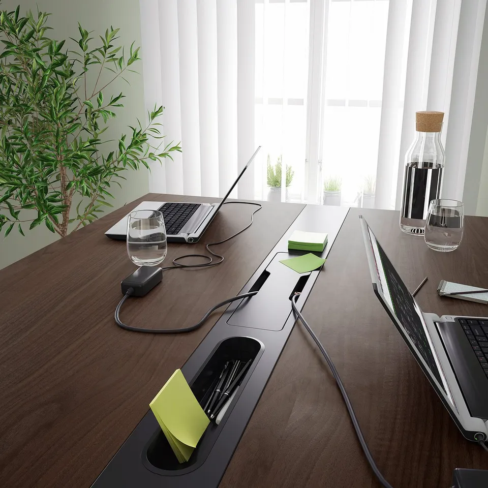 Conference table with built-in cable management, power modules, and footrest support, ideal for sitting or standing meetings.