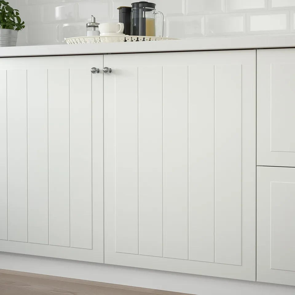 White kitchen cabinet with grooves, mounted on right, lacquered for stain resistance, easy to clean.