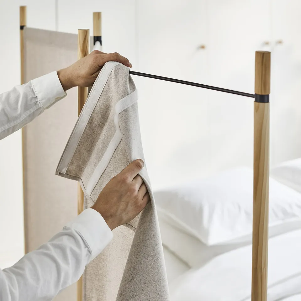 Person arranging a grey GLAMBERGET towel on a wooden rack.