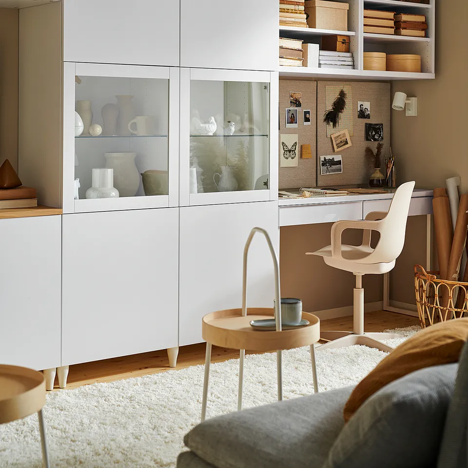 Modern living room with BESTÅ storage, displaying vases, books, and decor. Minimalist, organised space with light wood and neutral tones.