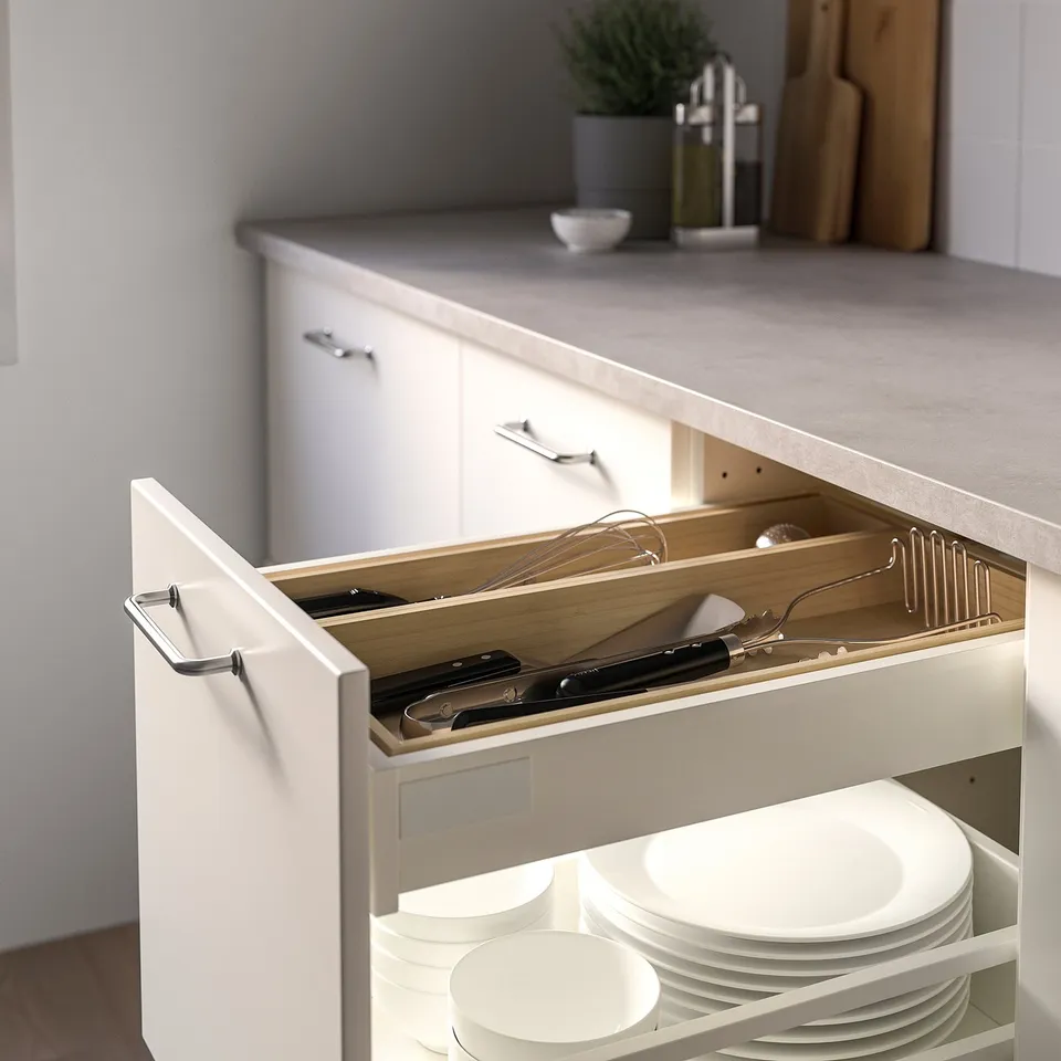 White kitchen drawer organiser with bamboo tray holding utensils and plates, mounted inside drawer.