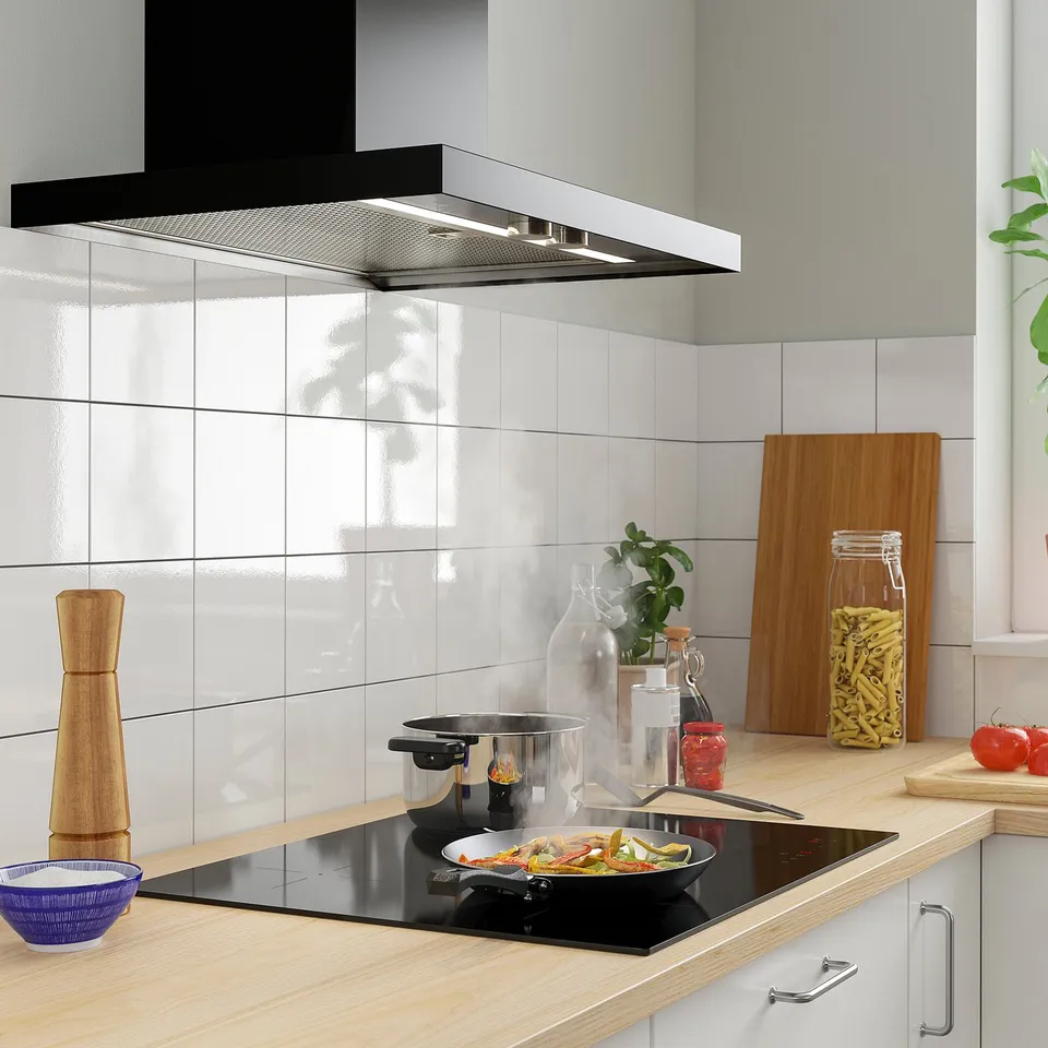 Modern kitchen with VILSTA induction hob, white tiles, wooden countertop, and cooking vegetables.