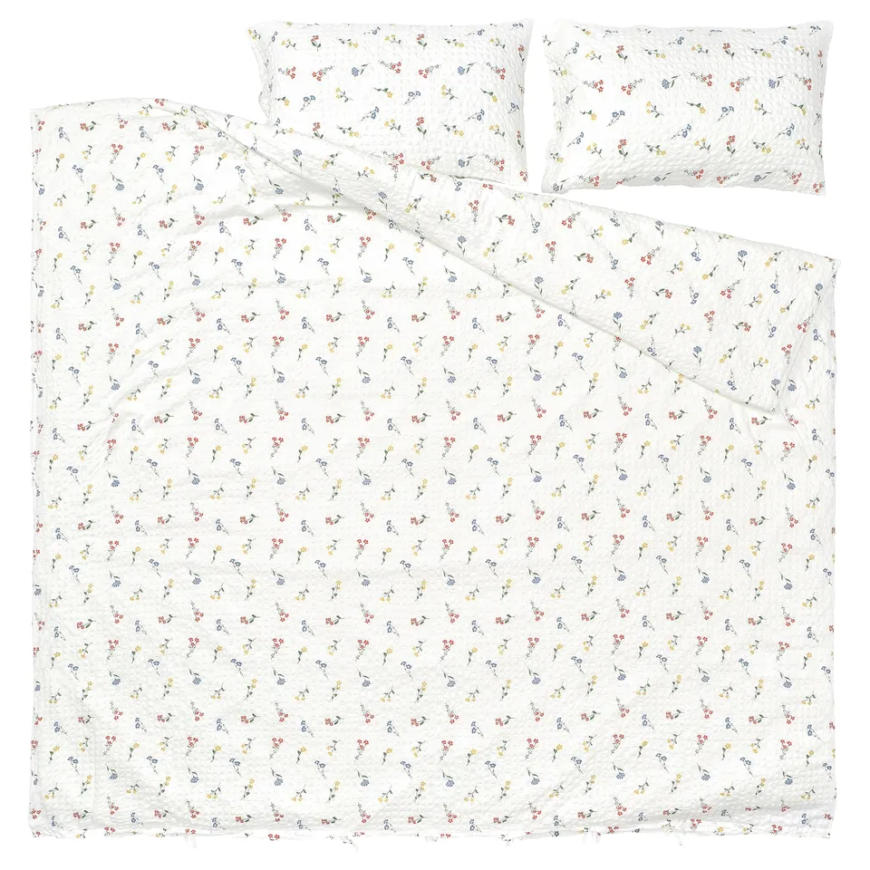 This image a PILDVÄRGMAL duvet set with white base, colourful floral prints, and seersucker texture, including a duvet cover and two pillowcases.