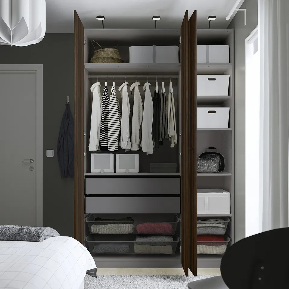 A modern, organised wardrobe with open doors showcasing hangers with clothes, shelves, and storage boxes.