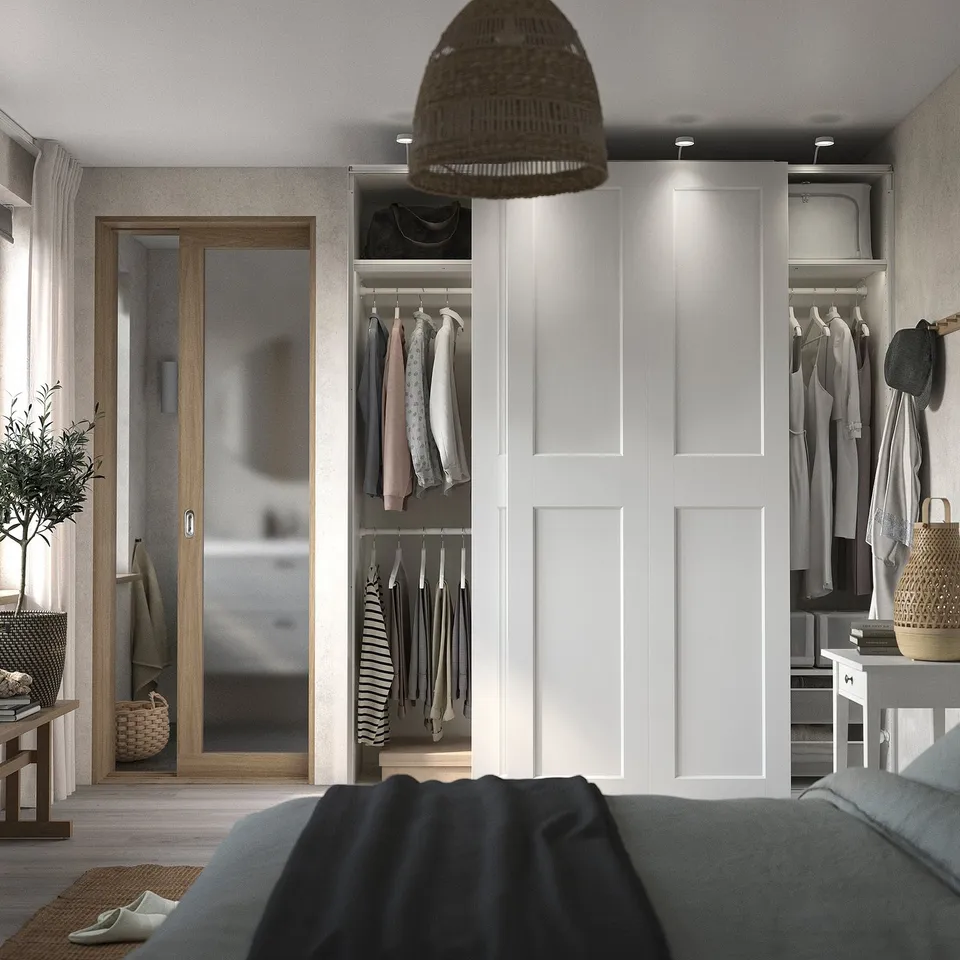 Modern bedroom with blue bed, open wardrobe showing clothes, and wooden door.