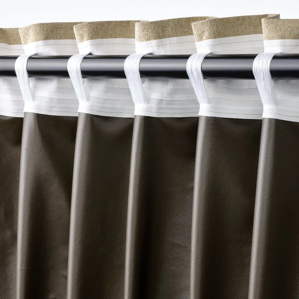 Close-up of curtain rod with white tab-top curtains hanging, providing room darkening and privacy.