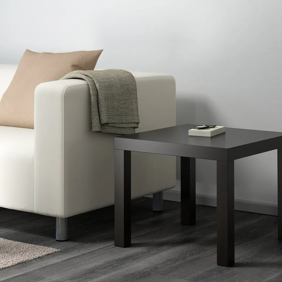 BLACK coffee table next to white sofa with grey blanket & book. Sleek, modern, medium size.