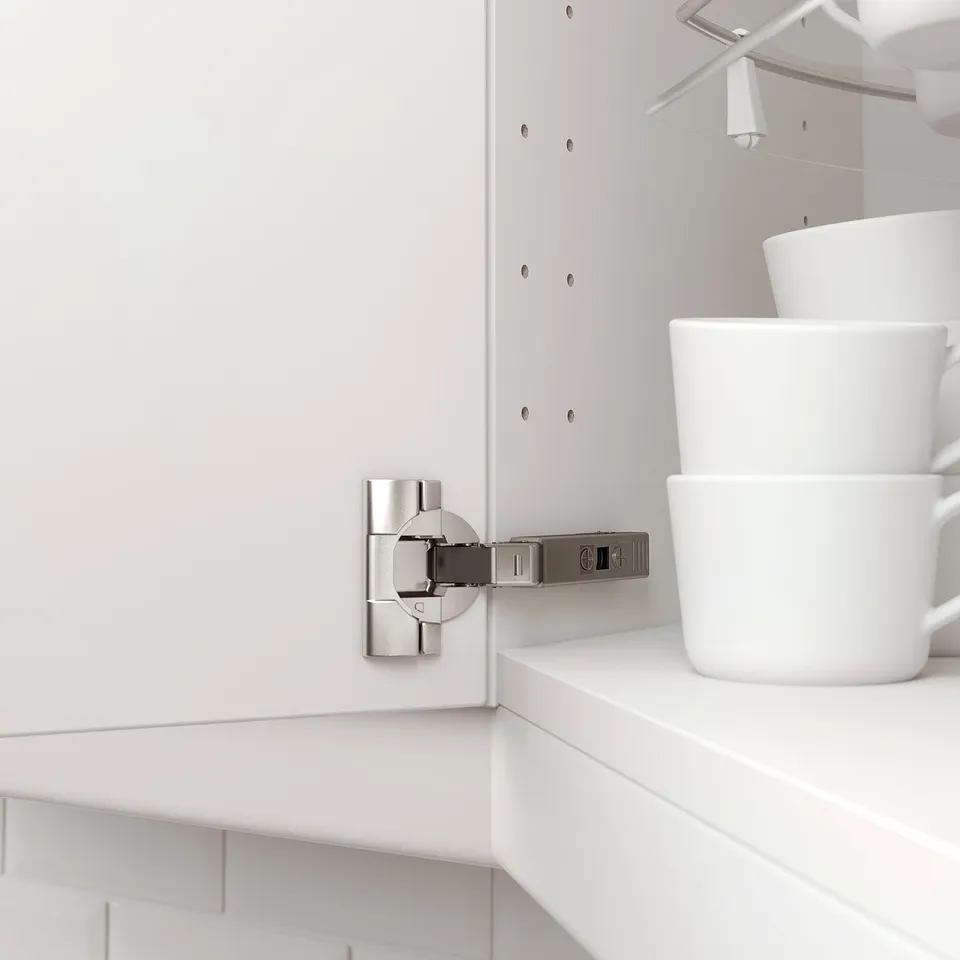 A close-up of a kitchen cabinet hinge attaches a door; it is adjustable and used for a corner unit.