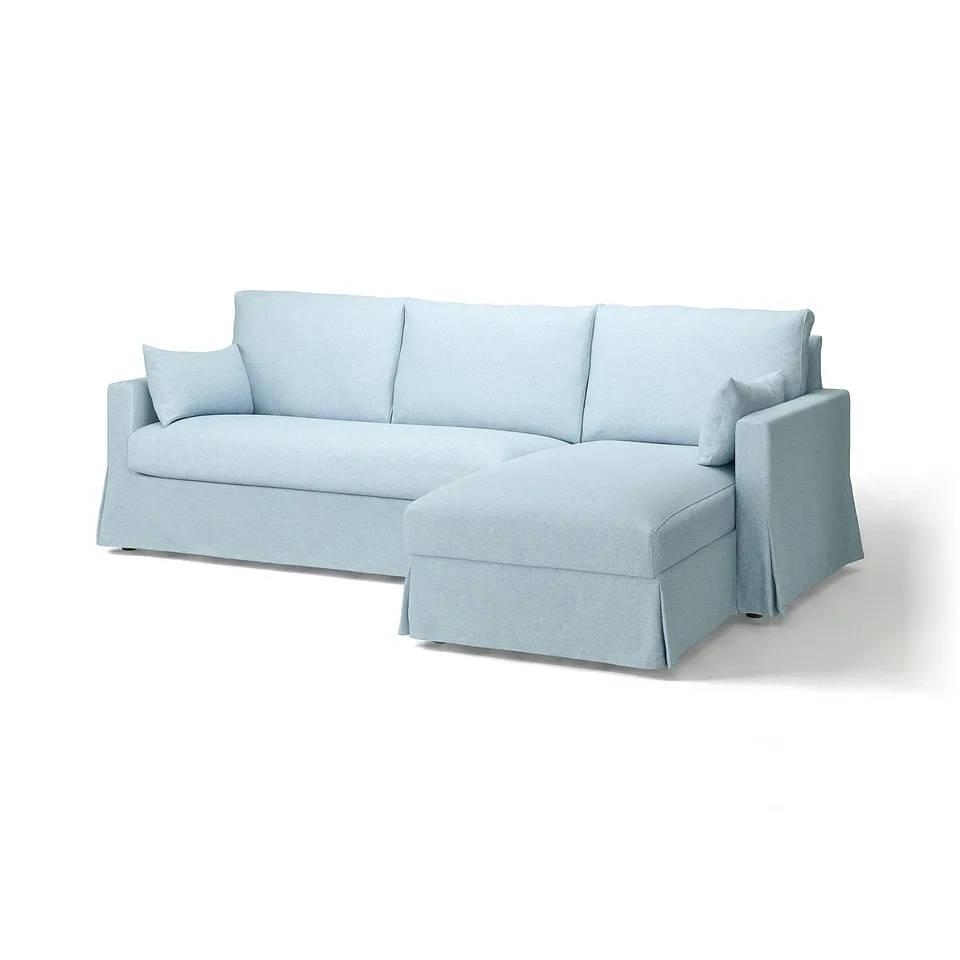 Light blue l-shaped sofa with clean lines, curved back, and hidden storage. Soft, modern design with removable covers.