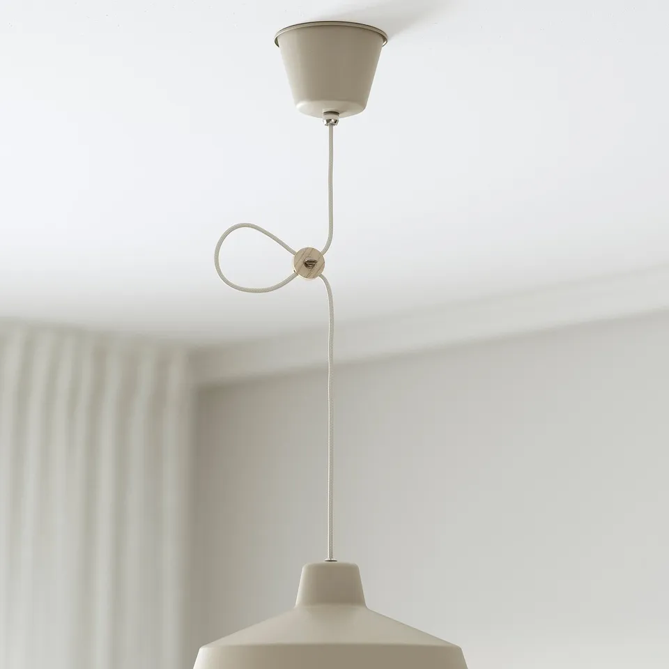 A beige pendant lamp hangs from a ceiling with an adjustable cord, providing directed light.