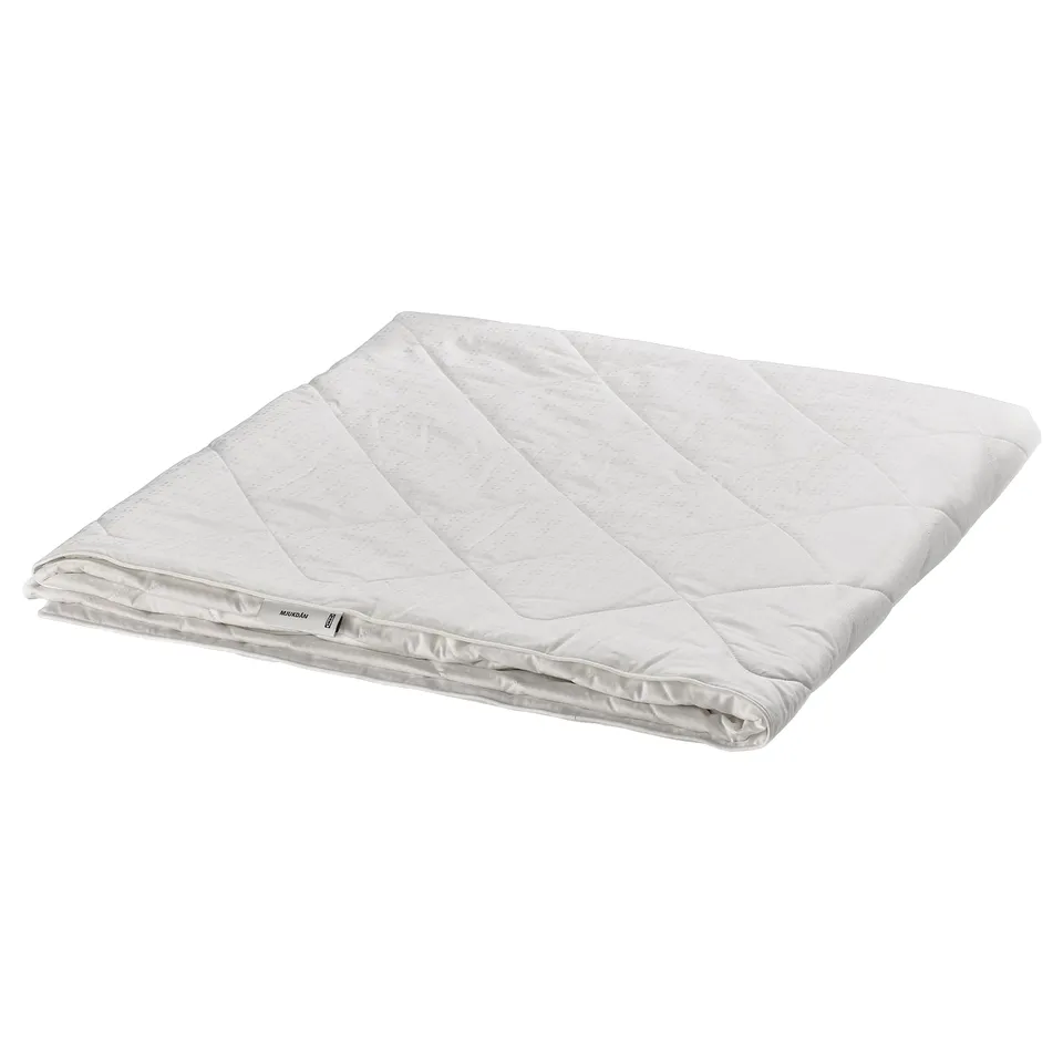 Folded white silk duvet by IKEA, soft cotton exterior, luxurious silk filling.