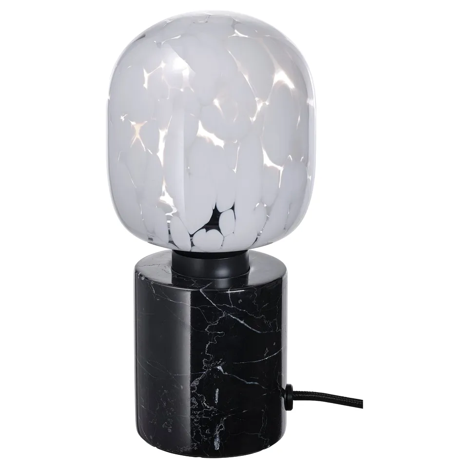 The MARKFROST lamp with a white marble base and a textured glass bulb, giving off a warm, diffused light.