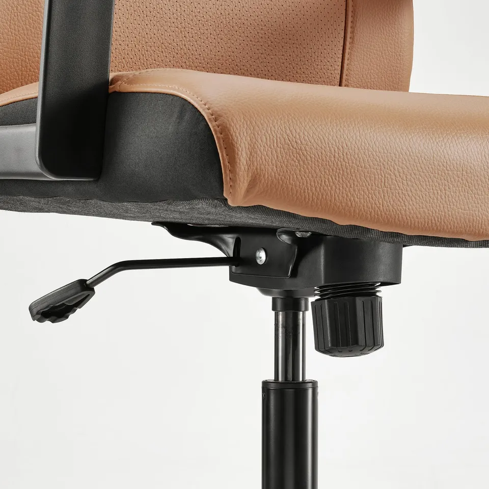 A close-up of an MILLBERGET office chairs armrest and height-adjustment mechanism.