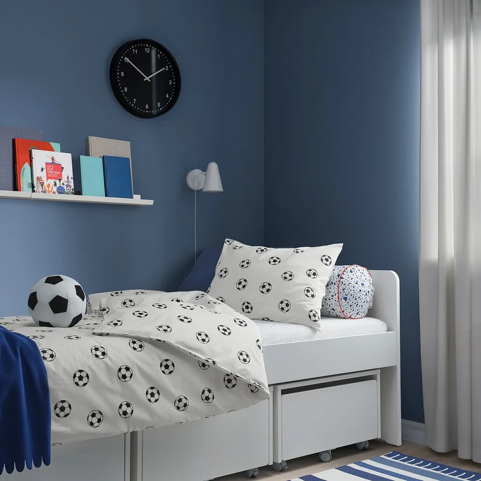 Soccer-themed bed, bookshelf, lamp, clock, blue walls.