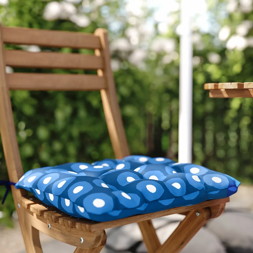 Blue patterned chair cushion on wooden outdoor chair.