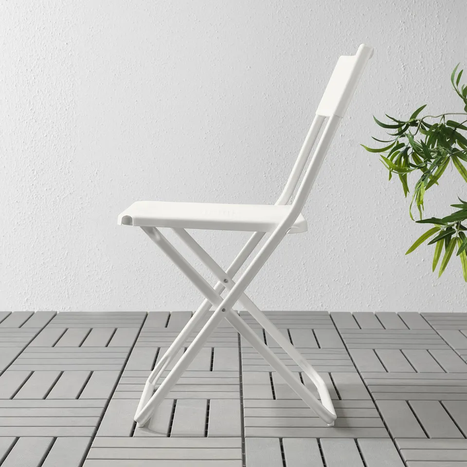 White folding chair on grey tiles. Simple, durable, portable design. Great for small spaces and outdoor use.