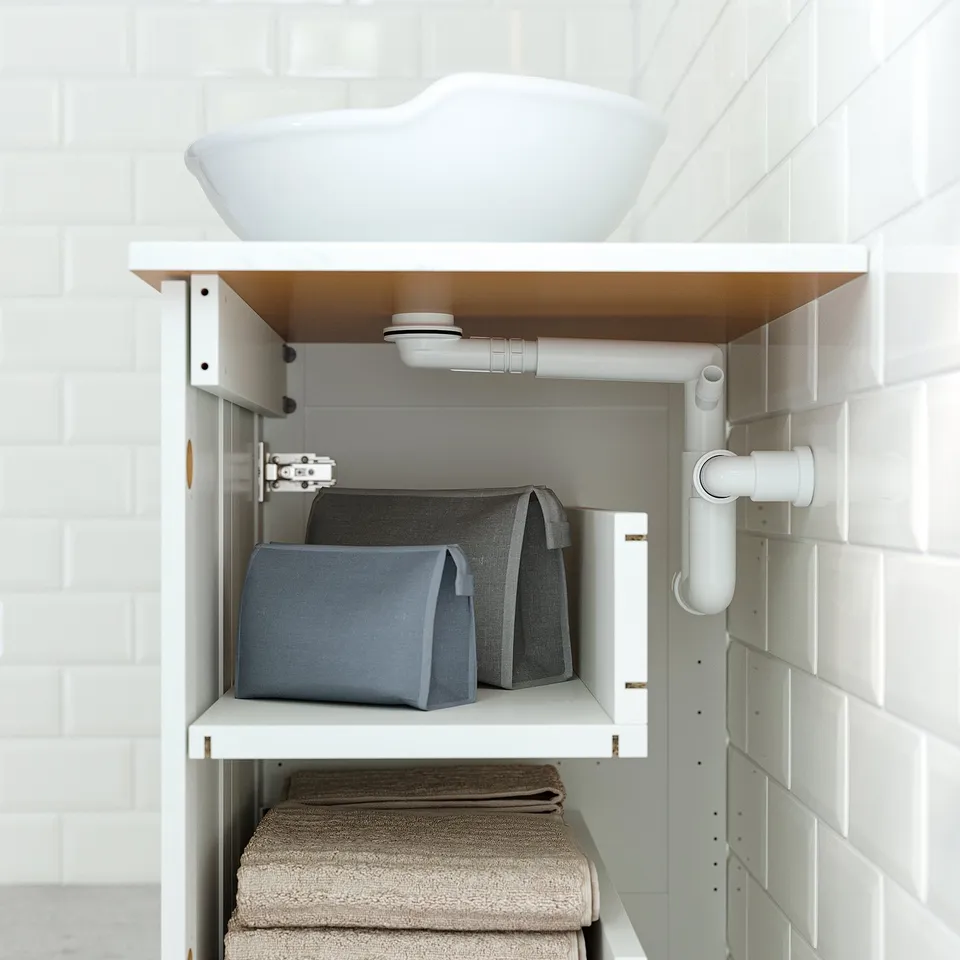 Under-sink storage with grey bins and folded towels.