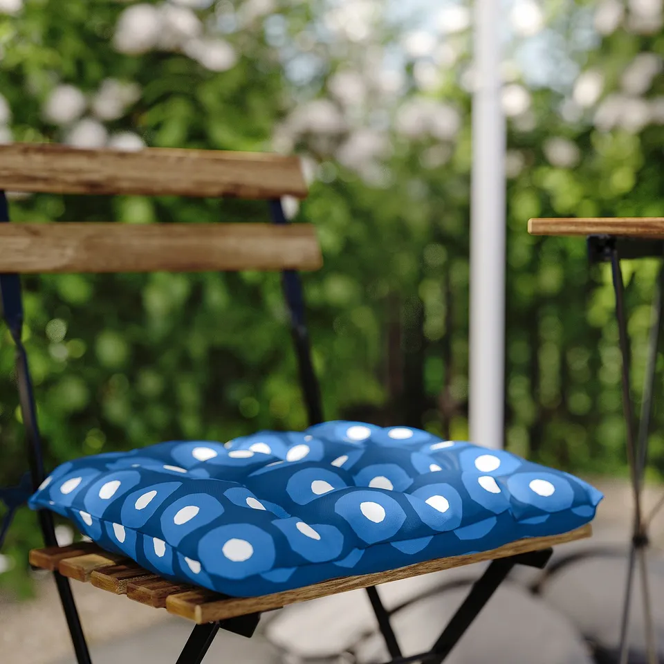 Blue and white patterned cushion on wooden outdoor chair.