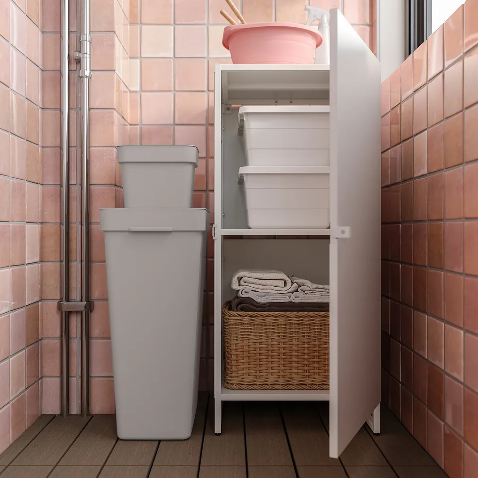 White metal shelf with multiple compartments and a wicker basket underneath, set against peach-hued tiled walls. Ideal for organised storage.