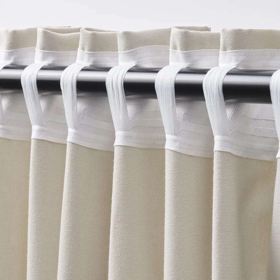 Close-up of beige curtains with rod pocket and pleats.